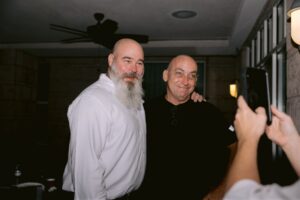 - Innocence Project of Florida Two men posing for a selfie indoors; the man on the left wears a white shirt and has a long gray beard, the man on the right wears a black shirt.